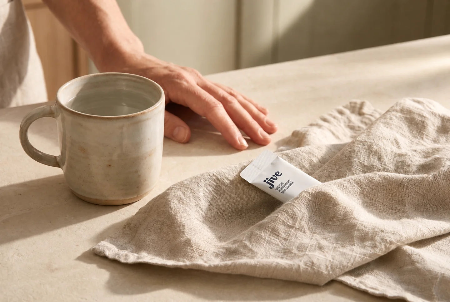A warm mug beside a Jive creatine stick on a linen napkin.