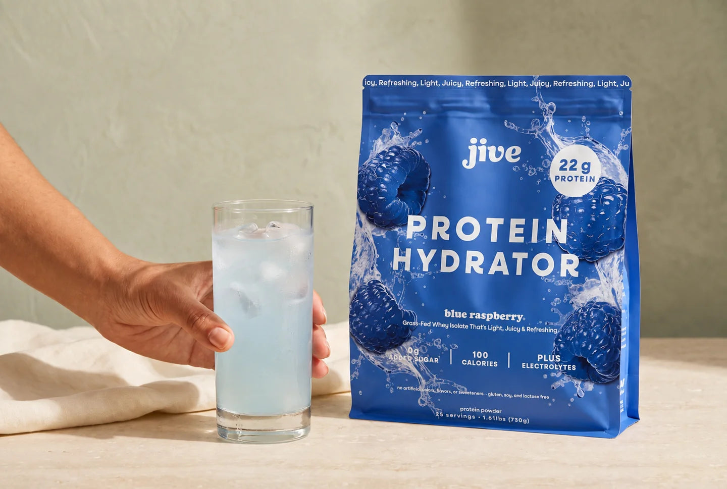 Blue Raspberry Protein Hydrator served over ice beside the pouch.